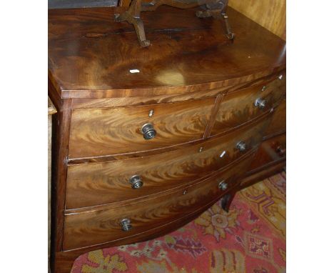 An early 19th Century mahogany bow fronted chest of two short over two long drawers with brass knob handles raised on splayed