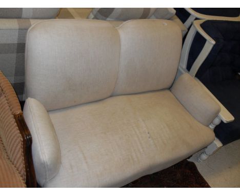A Victorian upholstered two seat sofa raised on three turned and ringed front legs to horn castors