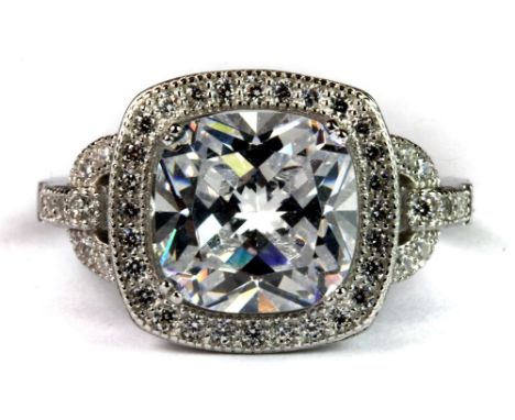 A silver ring set with a large cushion cut cubic zirconia and zirconia set shoulders.