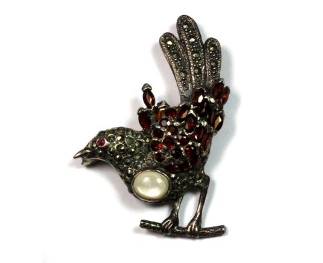A bird shaped silver brooch set with garnets and a ruby.