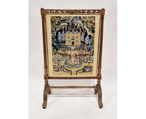Early 20th century firescreen with a foliate carved giltwood frame and woolwork panel of a country house in front of a lake, 
