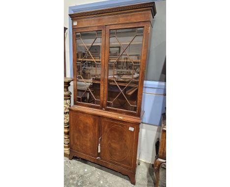 Regency-style mahogany and cross banded small library bookcase with moulded dentil cornice, two astragal glazed doors opening