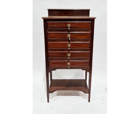 Edwardian mahogany music cabinet, the six drop front drawers with brass drop handles, with shelf below and raised on square t
