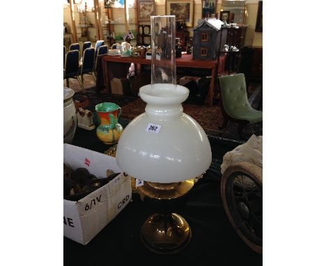 A brass oil lamp with opaque white glass shade.