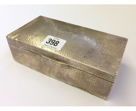 An early 20th century hammered silver cigarette box together with two silver spoons.