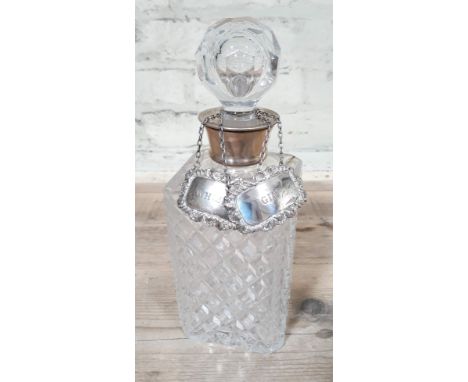 A cut glass decanter with hallmarked silver collar and two hallmarked silver decanter labels. 