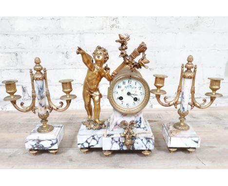 A French gilt metal and veined marble double spring driven mantle clock with candlestick garniture and mounted with a cherub 