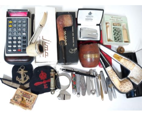 A mixed lot to include a Novus computer, vintage pipes, penknives, pens, a Ronson lighters, a meerschaum pipe, a naval badge 