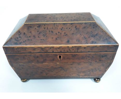 A 19th Century burr yew tea caddy of sarcophagus form, boxwood strung with parquetry inlay and four brass ball feet, length 2