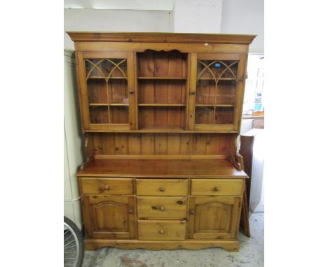 A contemporary pine kitchen dresser, the top with open central plate shelves flanked by glazed astrigal display doors with ar