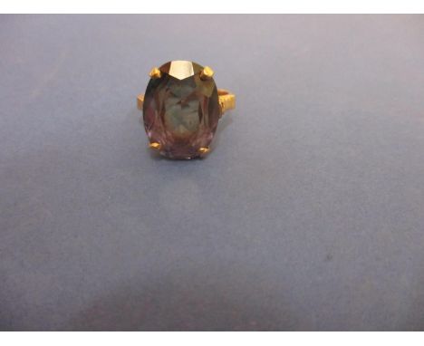 A yellow metal ring inset with an alexandrite coloured stone