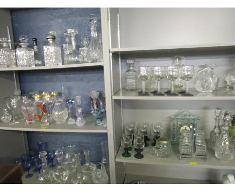 Five shelves of assorted cut and pressed glassware to include approximately twenty three decanters, a mantle clock, two pickl