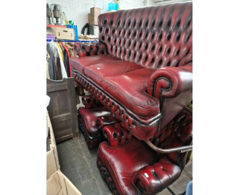 An oxblood red leather Chesterfield sofa and two matching armchairs. 