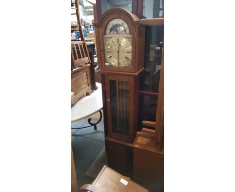 An oak cased chiming grandmother clock with brass face and moon dial, complete with weights and pendulum. 