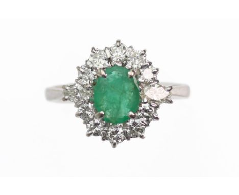 An emerald and diamond oval cluster ring, the oval mixed-cut emerald claw set within a marquise and round brilliant twelve st