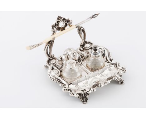 An inkwellPortuguese silver Romantic era raised and engraved decoration of volutes, foliage and classical mask with glass ink