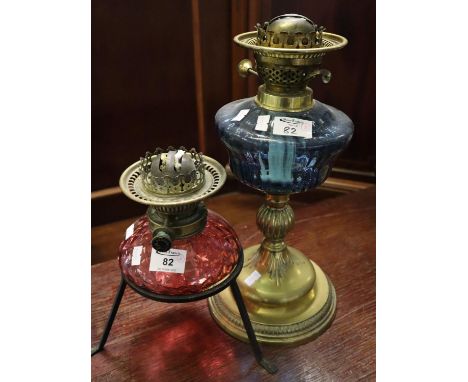 Brass double burner oil lamp on coloured glass reservoir with wrought metal three legged base, together with an early 20th Ce
