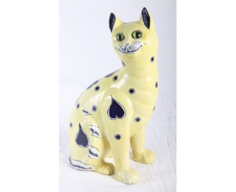 A Galle style ceramic model of a seated cat decorated in blue on a pale yellow ground, glass eyes, 14" high