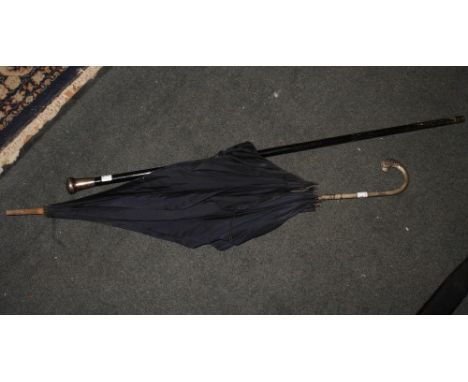 An ebonised walking stick with engraved silver pommel and a lady's umbrella with white metal handle decorated Celtic decorati