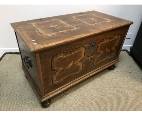 An oak and parquetry-inlaid coffer in the 17th Century style, the starburst panel decorated top over a bird in a rectangular 