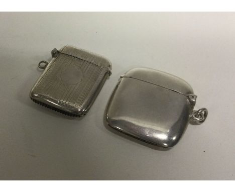 An engine turned silver vesta case together with a plain example. Approx. 35 grams. Est. £25 - £30.
