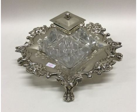 A heavy Victorian silver and glass inkwell on feet chased with flowers. Sheffield 1860. By Henry Wilkinson &amp; Co. Approx. 