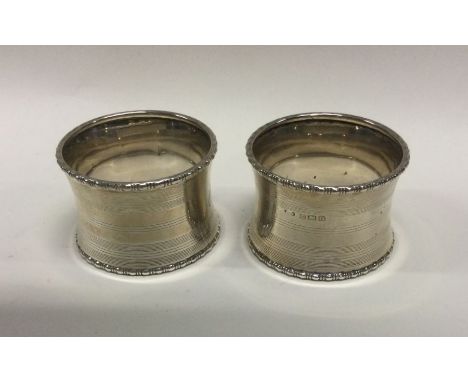 A heavy pair of engine turned silver napkin rings with reeded decoration. Approx. 40 grams. Est. £20 - £30.