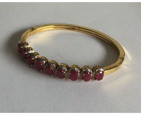 A silver gilt hinged bangle mounted with nine rubies. Approx. 21 grams. Est. £30 - £40.