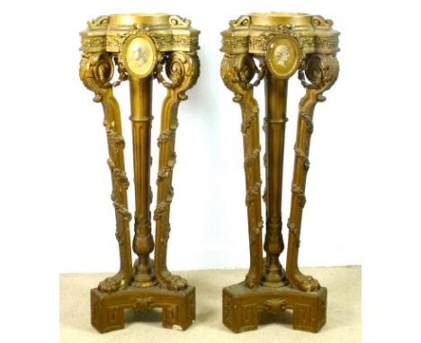 A pair of Victorian jardiniere stands, the tops with painted portrait plaques, raised on a central column, three leaf scroll 