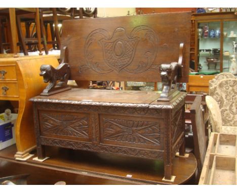 An early 20th Century carved oak Monks bench, the top/back on lion supports above a box base with hinged lid. 