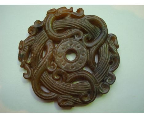 A Chinese nephrite jade bi disc pendant, pierced and carved with scrolling dragons. 