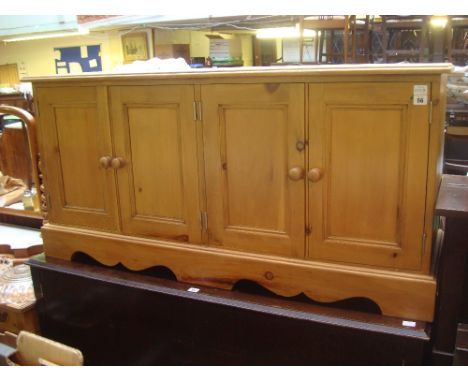 A low pine cupboard with two pairs of panelled doors on bracket base. 