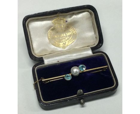 A pearl and blue stone brooch of crossover design. Approx. 3 grams. Est. £30 - £40.