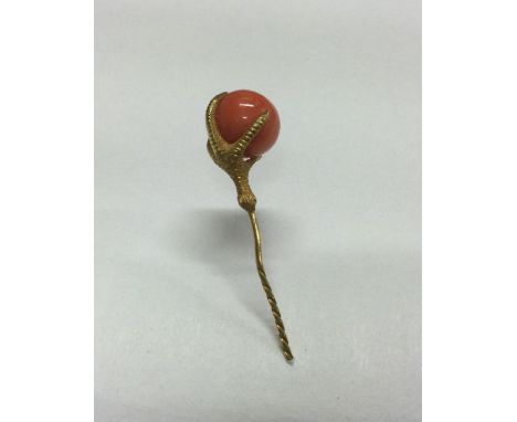 A good Antique high carat gold stick pin in the form of a claw clutching a coral bead. Approx. 5 grams. Est. £30 - £50.