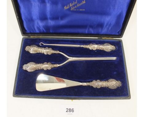 A silver handled shoe horn, button hook and glove stretchers with embossed decoration, boxed, Birmingham 1914, By G &amp; C L