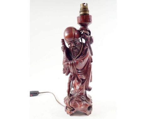 A carved wood oriental table lamp in form of figure of a man