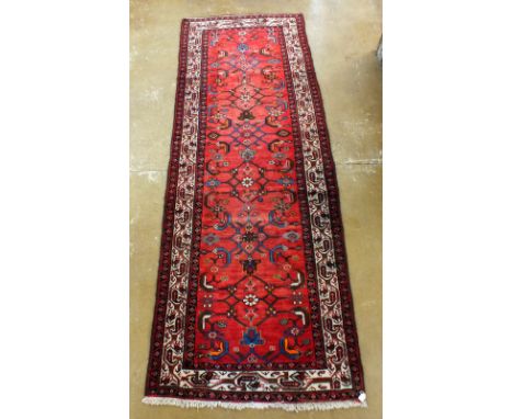 A red washed Iranian runner with an all-over floral pattern, 300 x 110cm 