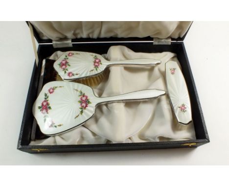 A vintage floral enamel four piece dressing table set including mirror, two brushes and a comb, cased