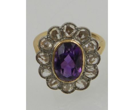 A yellow gold, diamond, and amethyst cluster ring, the oval cut central amethyst surrounded by twelve old cut diamonds in an 