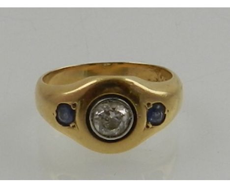 An 18 carat yellow gold, diamond, and sapphire ring, the round cut central diamond of approx. 0.4 carats, flanked by two pave