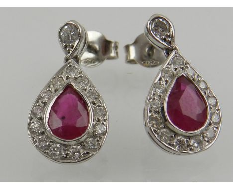 A pair of white gold, diamond, and ruby cluster pear drop stud earrings.