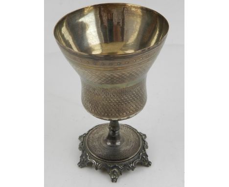 A Middle Eastern white metal cup, having engine turned design to top, raised on circular base, having six scrolling feet.