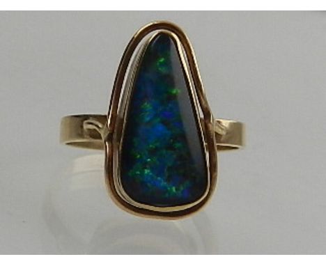 A 9 carat yellow gold ring, set with a doublet opal of irregular shape. 