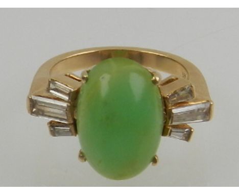 A 14 carat yellow gold, diamond, and jade ring, the oval cabouchon jade flanked by six tapered baguette cut diamonds