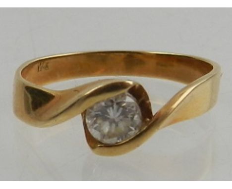 A yellow metal and solitaire diamond crossover style ring, the stone of approx 0.33 carats, the shank stamped 14K.