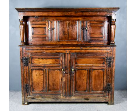 A 17th Century Panelled Oak Court Cupboard, the upper part with moulded cornice, on turned supports and cupboard enclosed by 
