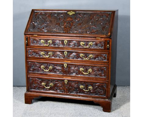 A George III Mahogany Bureau, the front later carved, the slope carved with green man and leaf scroll ornament enclosing five