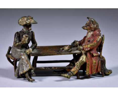 A Cold Painted Bronze Anthropomorphic Group comprising - a fox dressed in hunting pinks seated at a table with lady goose, he