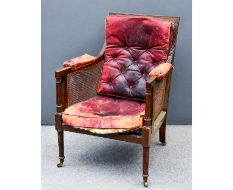 A George III Mahogany Square Back Bergere Armchair, with reeded framing, cane panelled seat, back, and sides, on turned and r