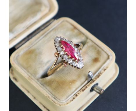 A Victorian ruby and diamond ring set with a central pointed oval ruby surrounded by fourteen old European cut diamonds to a 